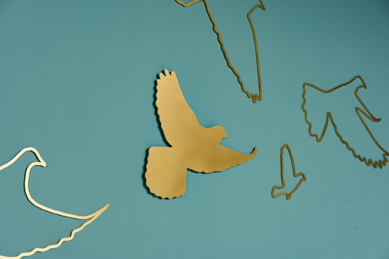 Middle Eight - Covent Garden - Preferred Hotels And Resorts London Kültér fotó The photo shows a collection of metallic gold bird silhouettes against a solid turquoise background. The birds are depicted in various positions and styles, showcasing different species and flight postures. Some silhouettes are more detailed, while o